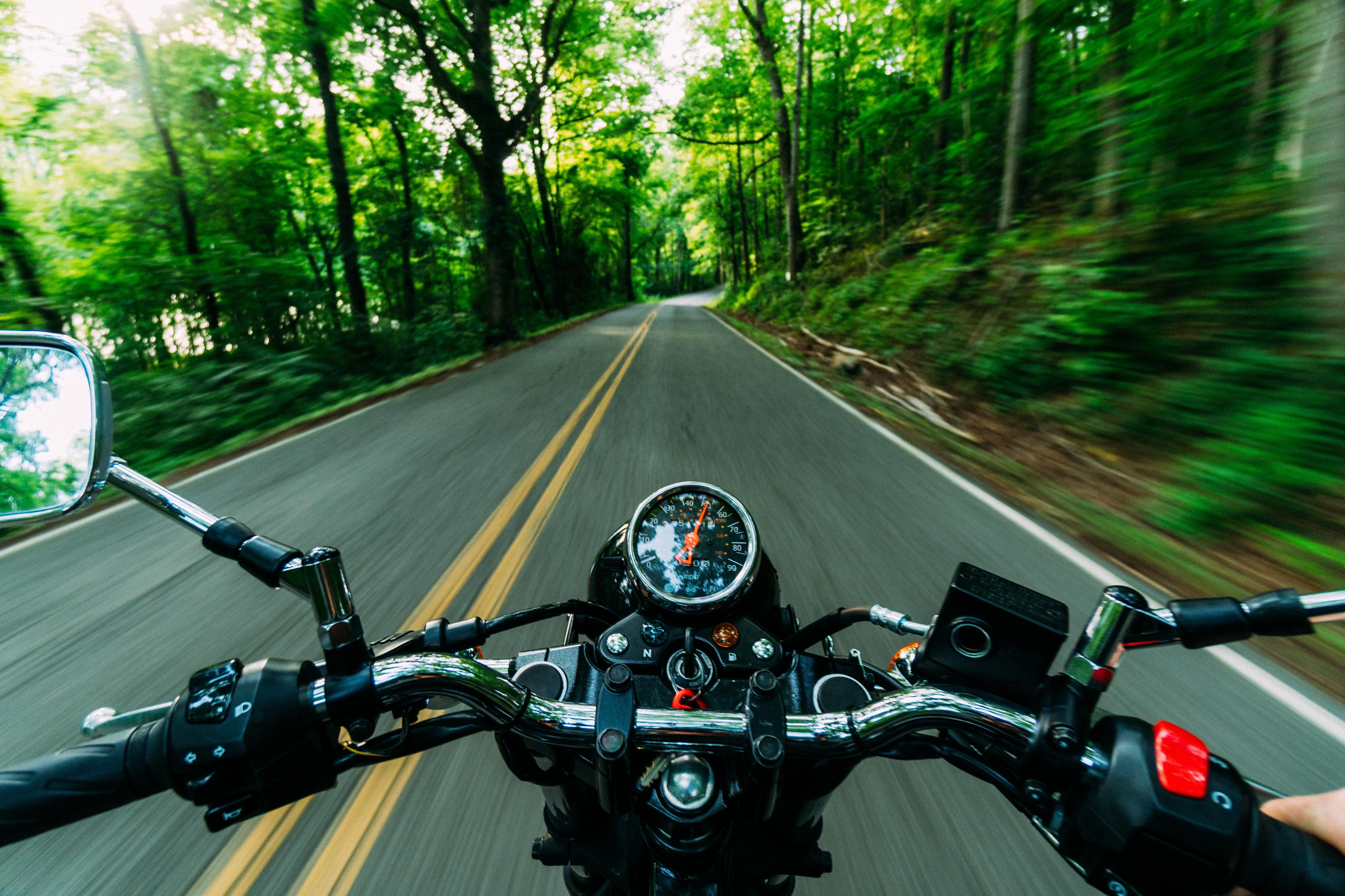 Uma moto dirigindo em uma estrada com árvores