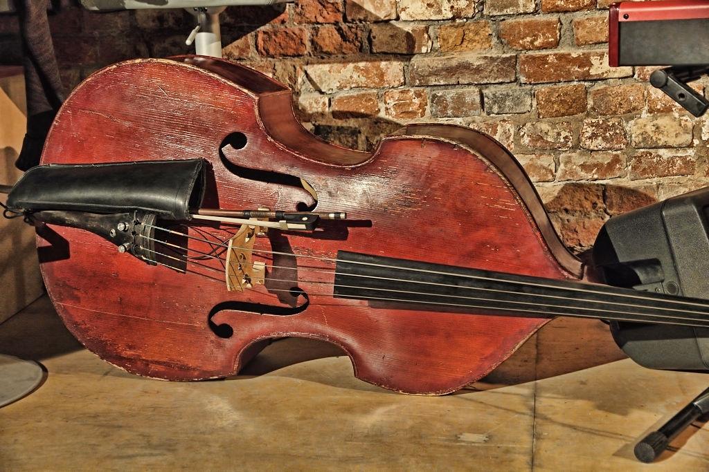 Contrabaixo acústico no palco, perto da uma parede velha de tijolos.