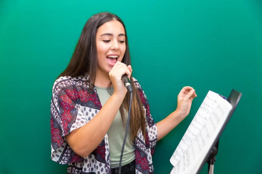 Jovem garota aprendendo os fundamentos do canto como respiração, postura e dicção.