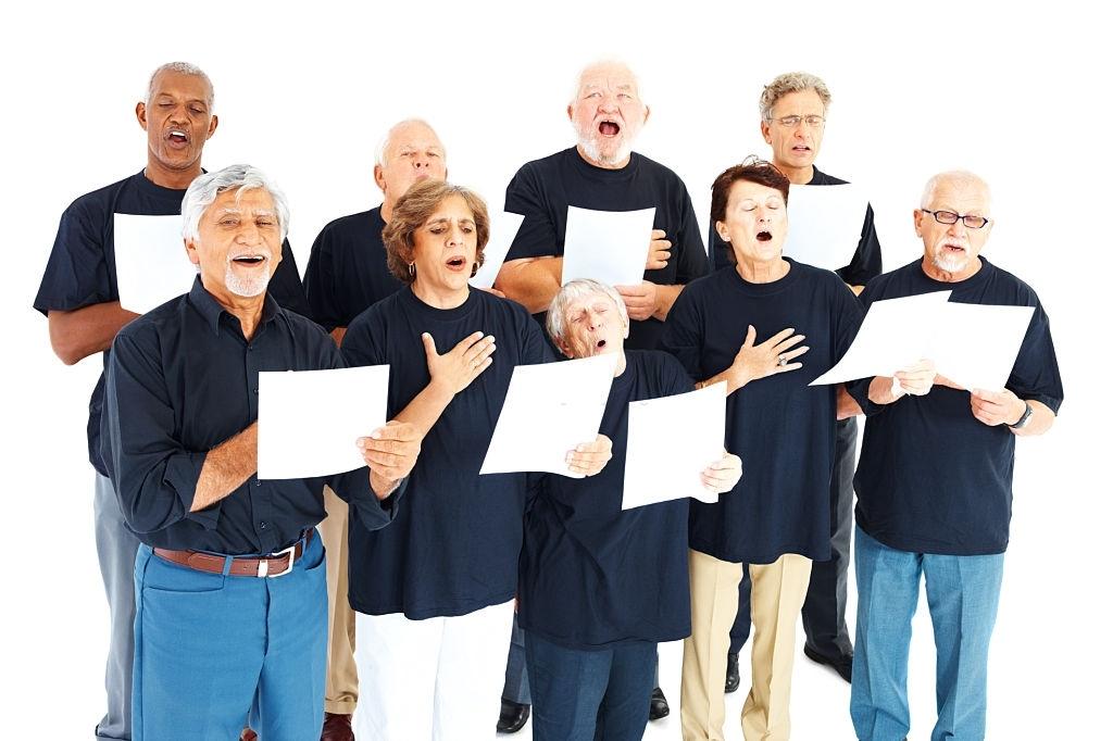 Idosos de um coral cantando o hino nacional.