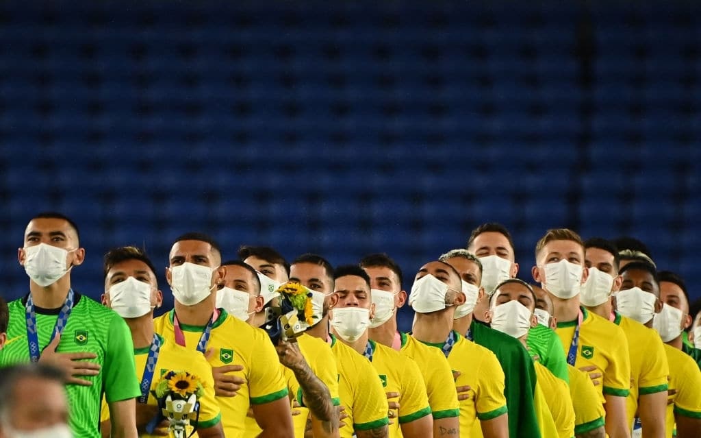 Seleção brasileira no pódio cantando o Hino Nacional durante a cerimônia de medalhas dos Jogos Olímpicos de Tóquio em 2020.