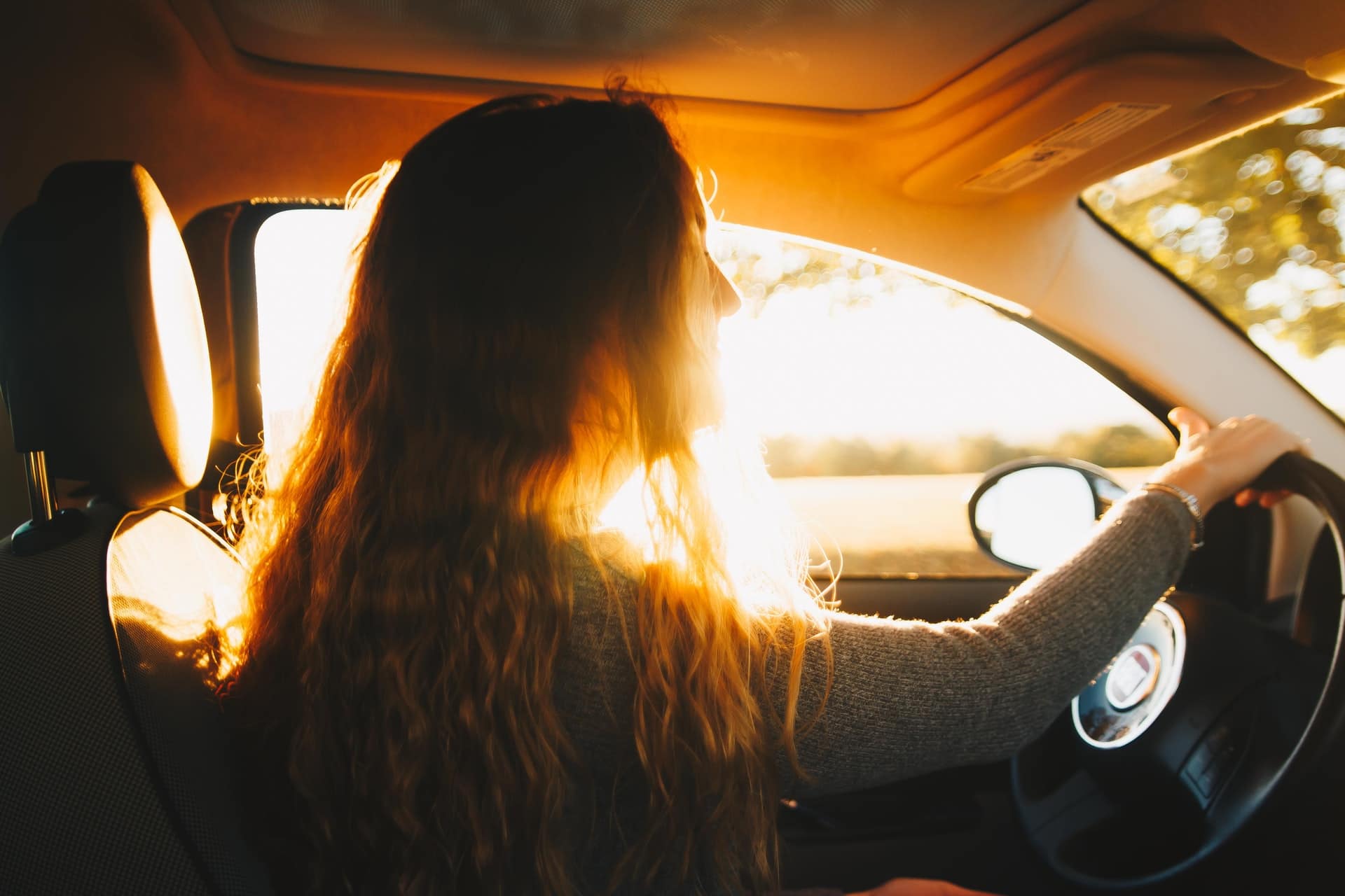 Moça de cabelo comprido dirigindo um carro