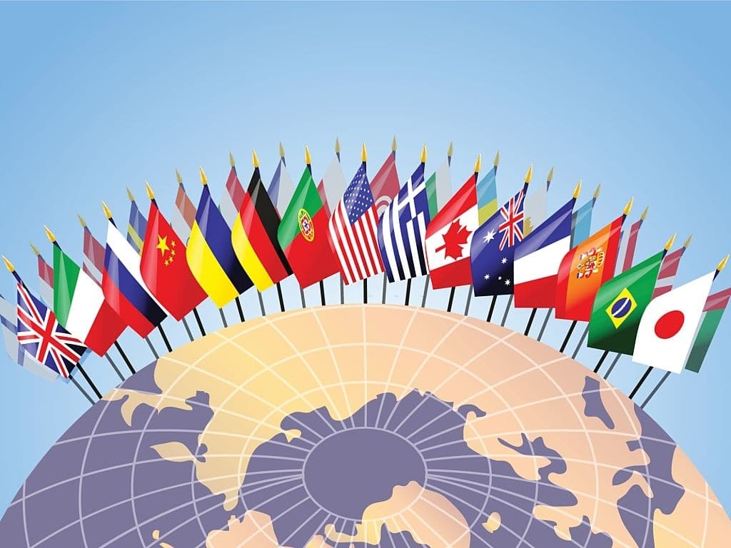 Bandeiras de diversos países fincadas sobre o globo terrestre.
