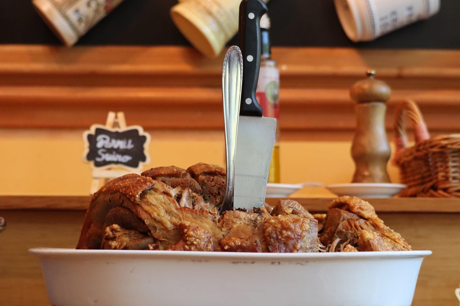 Culinária natalina, pratos típicos do Natal, pernil suíno com uma faca e um garfo .