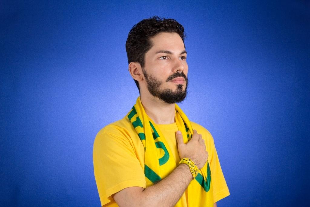 Torcedor brasileiro está ouvindo o hino nacional com mão no peito.
