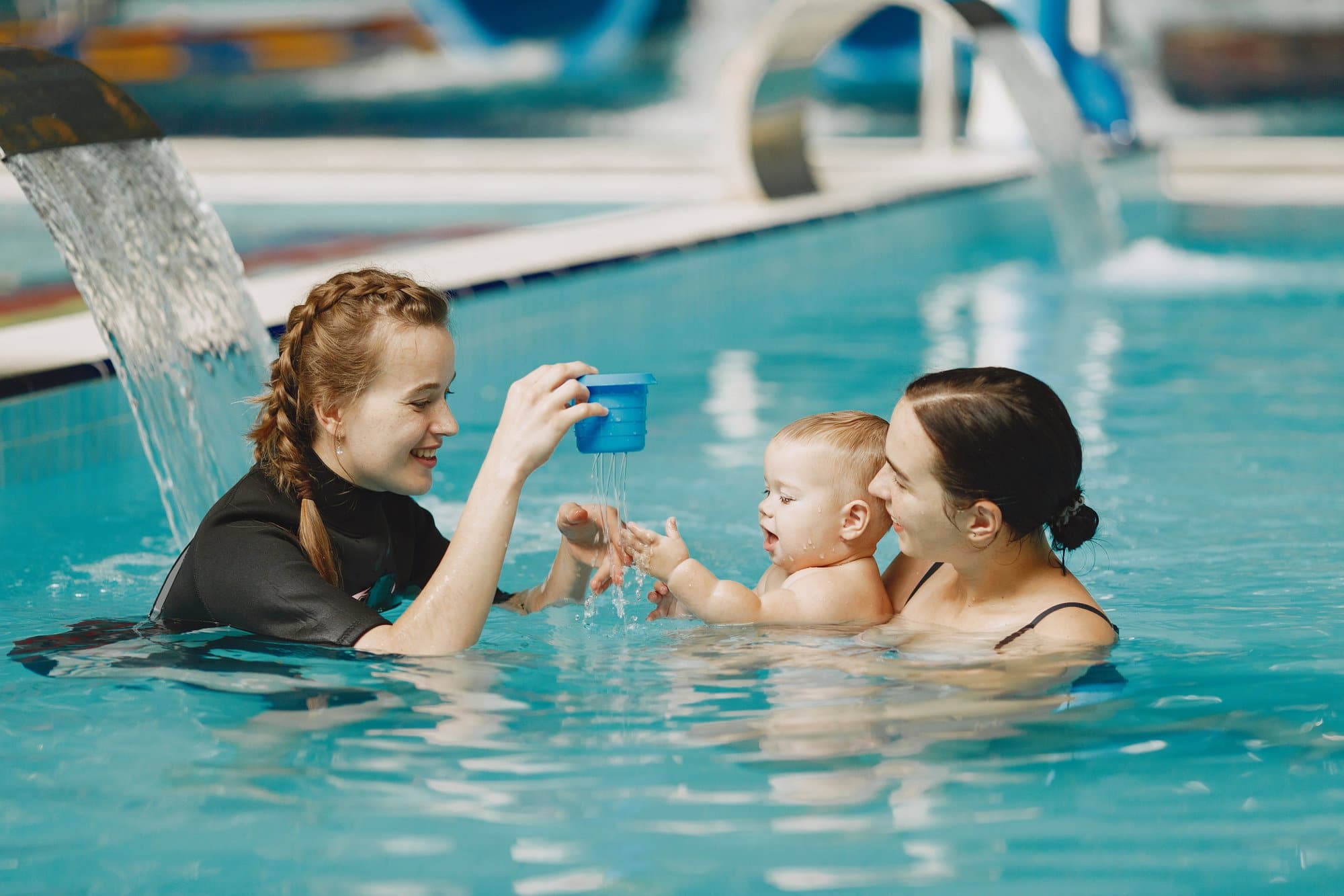 bebê brincando na piscina com mae e professora de natação
