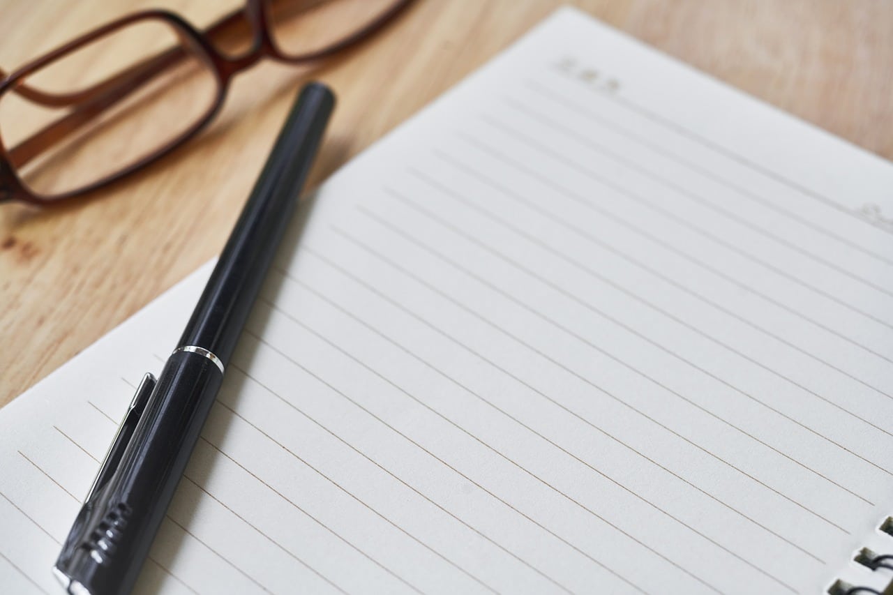 Caderno em branco com caneta e óculos