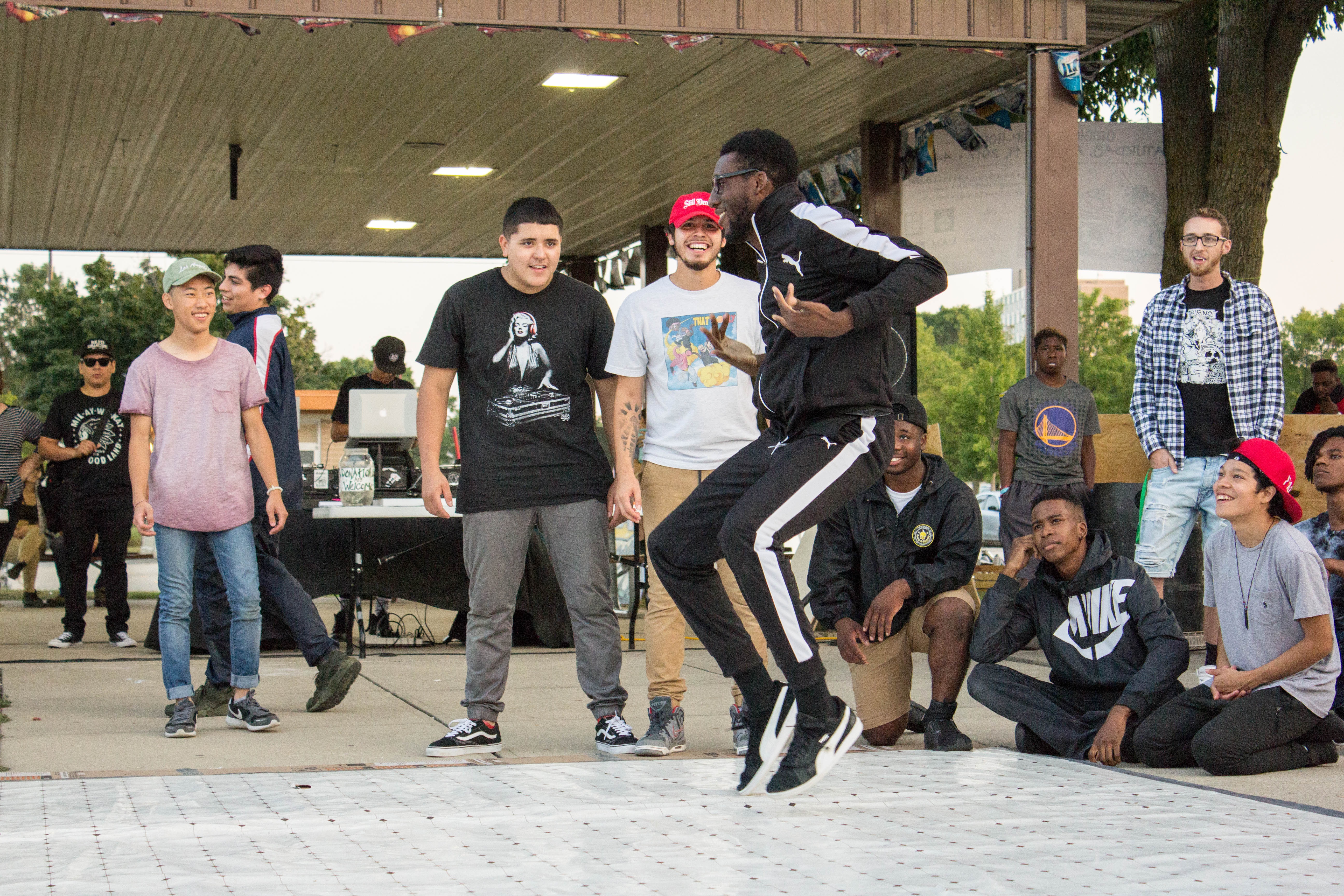 Homem dançando street dance em roda com os amigos. 