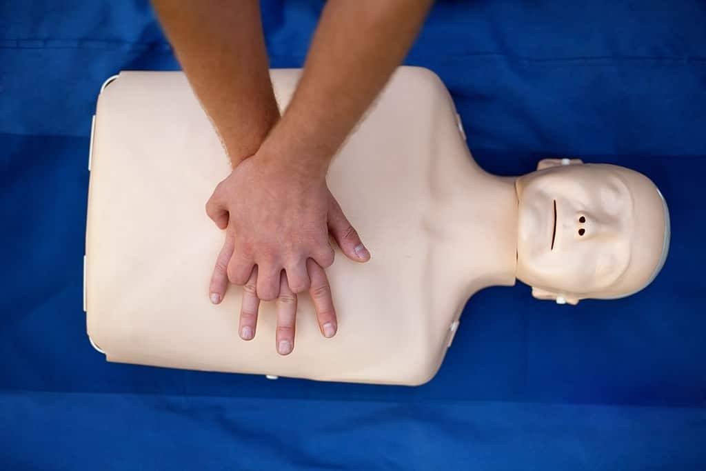 Imagem das mãos de uma pessoa fazendo compressões em um boneco de primeiros socorros.