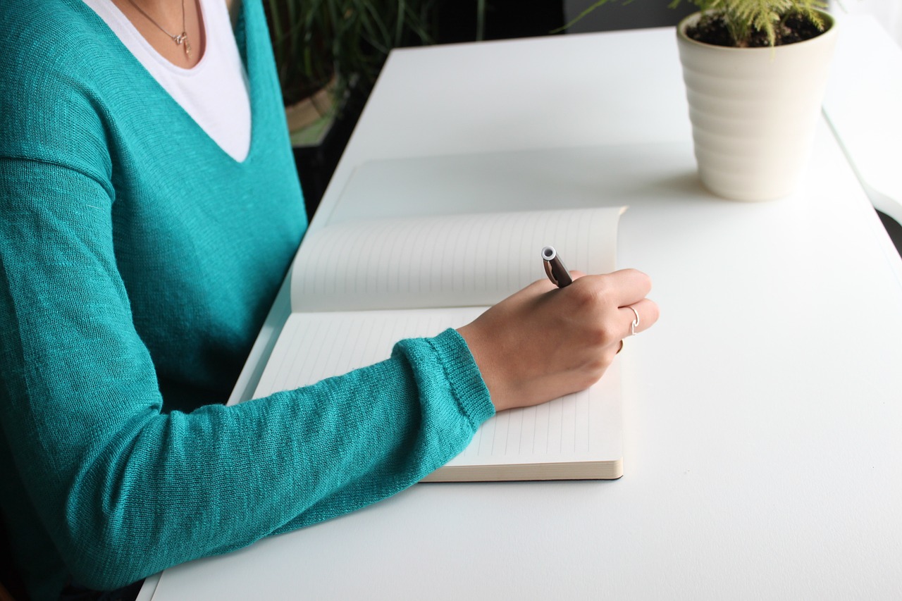 Mulher sentada escrevendo em um caderno em branco
