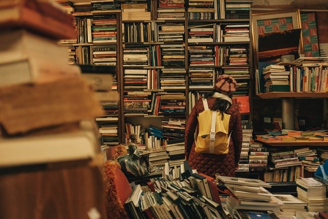 Pessoa com mochila amarela procura por livro em livraria