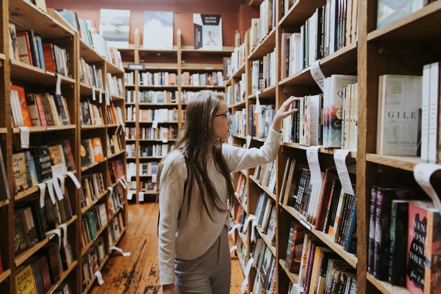 Menina escolhendo livro na biblioteca