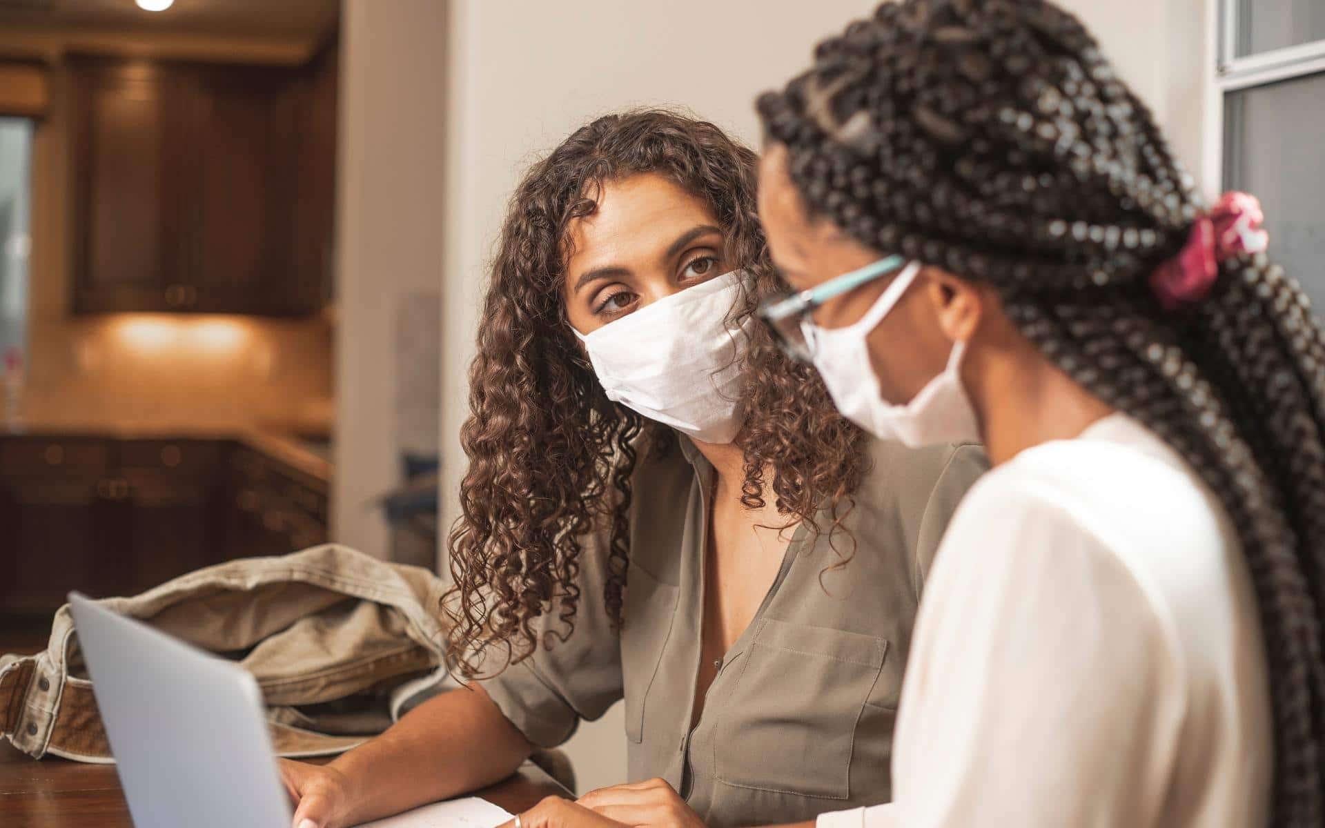 professora e aluna usando máscaras cirúrgicas em frente ao computador