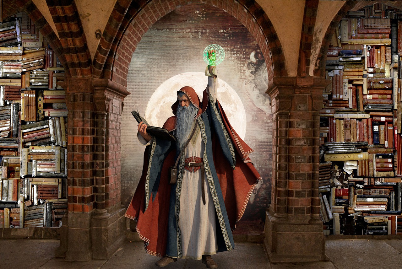 Idoso de barba longa e roupas medievais está em uma biblioteca cheia de livros segurando um grande livro em uma mão e com a outra mão levantada, tocando um símbolo verde mágico.