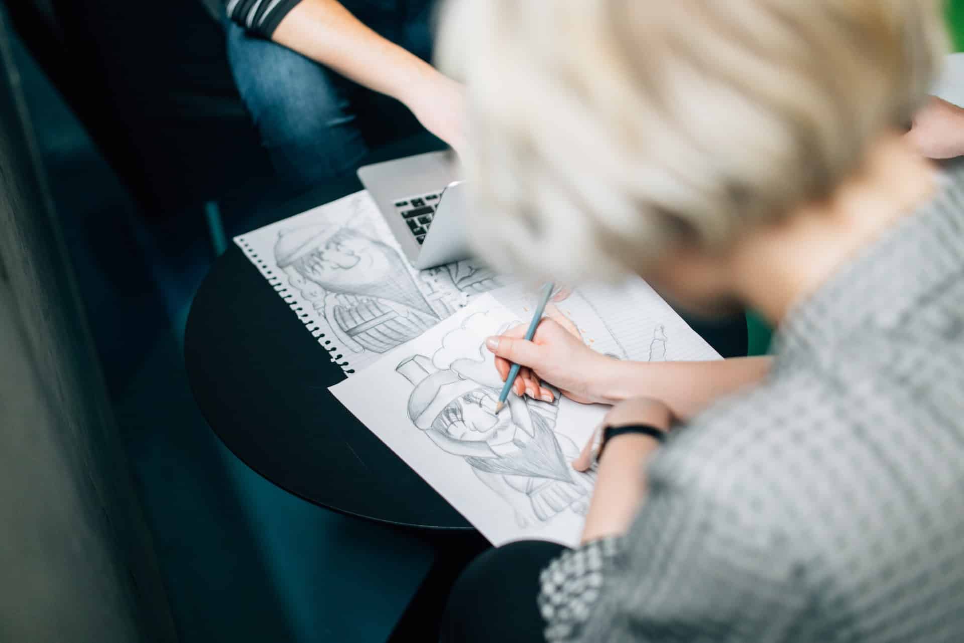 Foco da mão de uma mulher caucasiana desenhando em caderno
