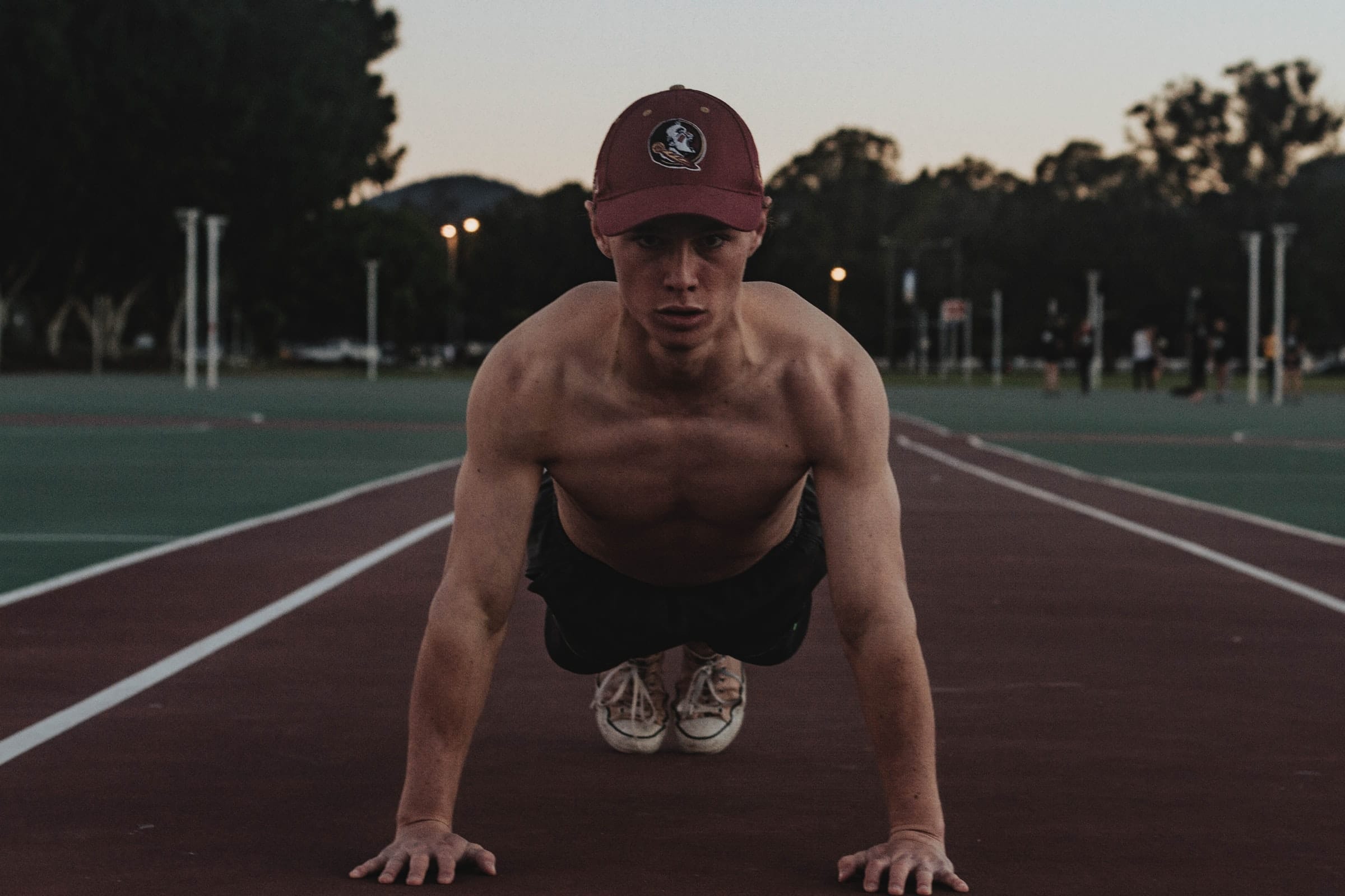 Homem flexionando os braços em pista de corrida.
