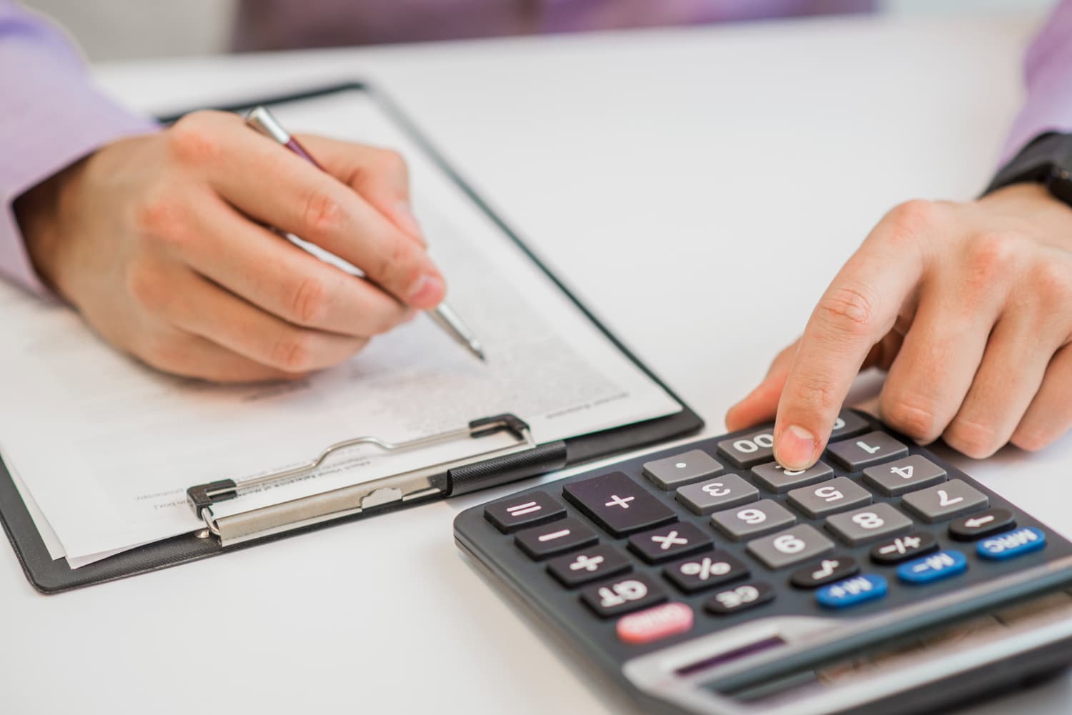 Mãos em destaque calculando e anotando em uma folha as informações