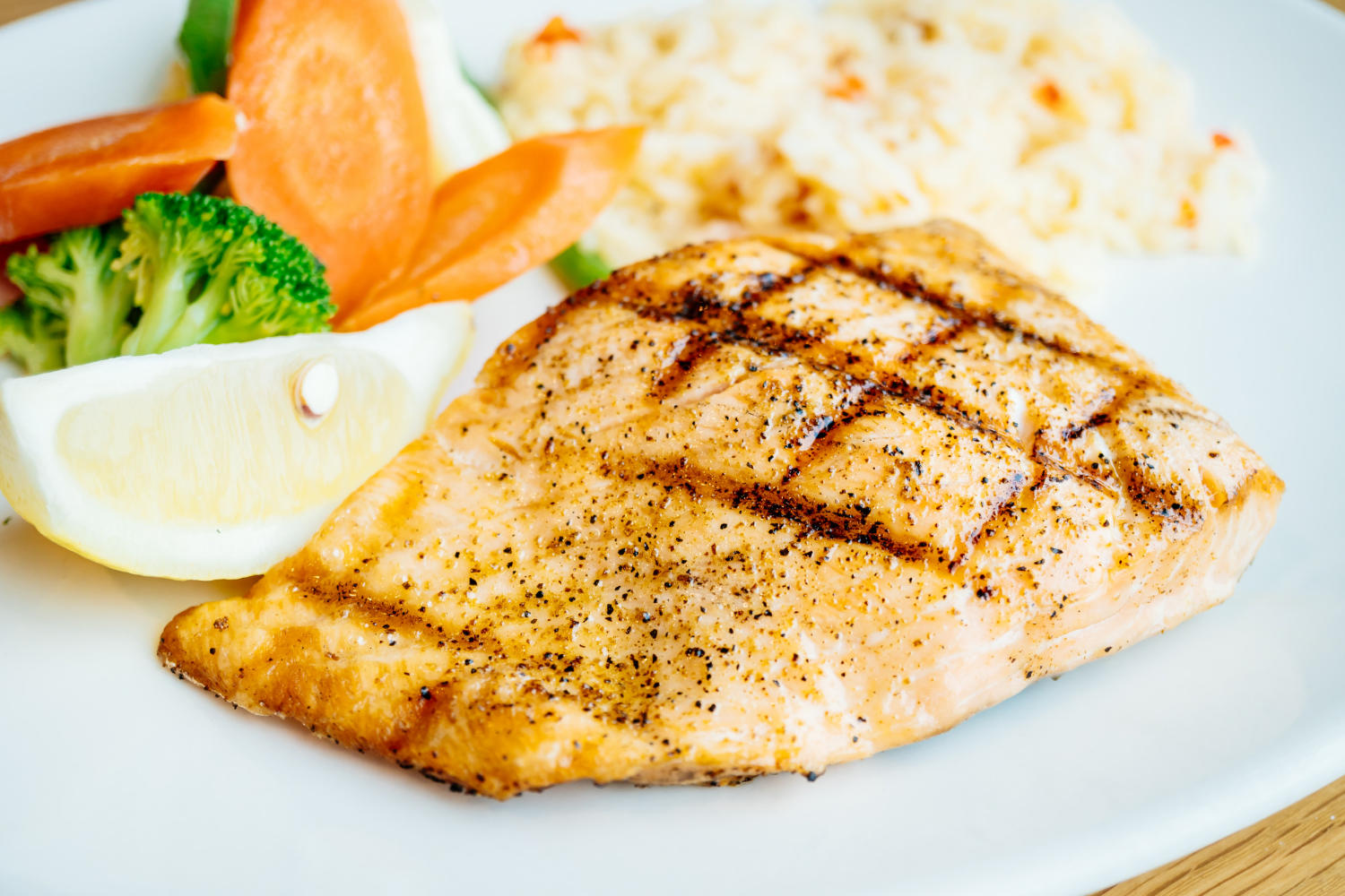 Filé de peixe com arroz e legumes no prato.