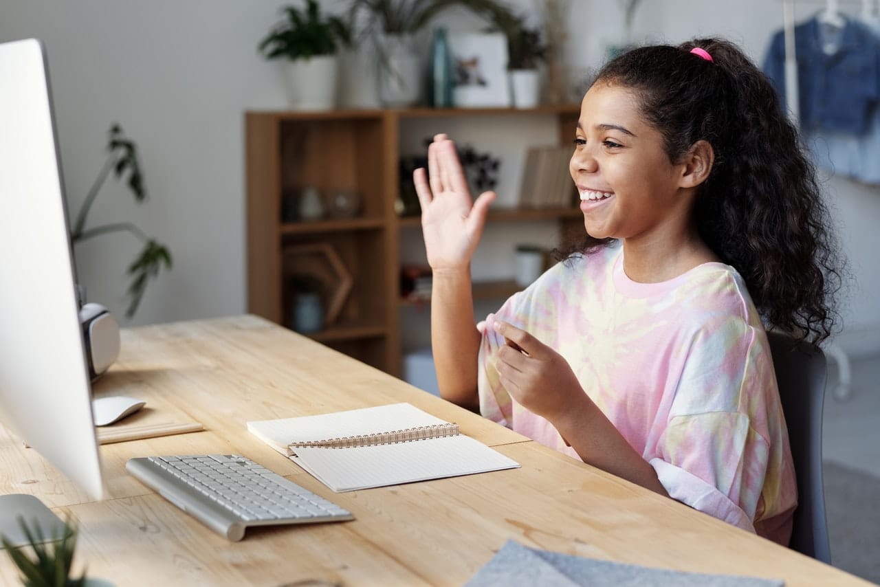 Criança feliz acena para tela do computador