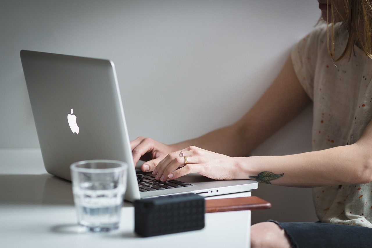 Mulher digita em computador laptop colocado sobre a mesa
