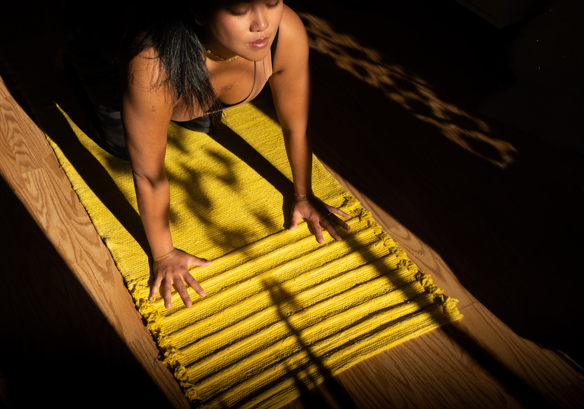 mulher praticando yoga em um tapete amarelo