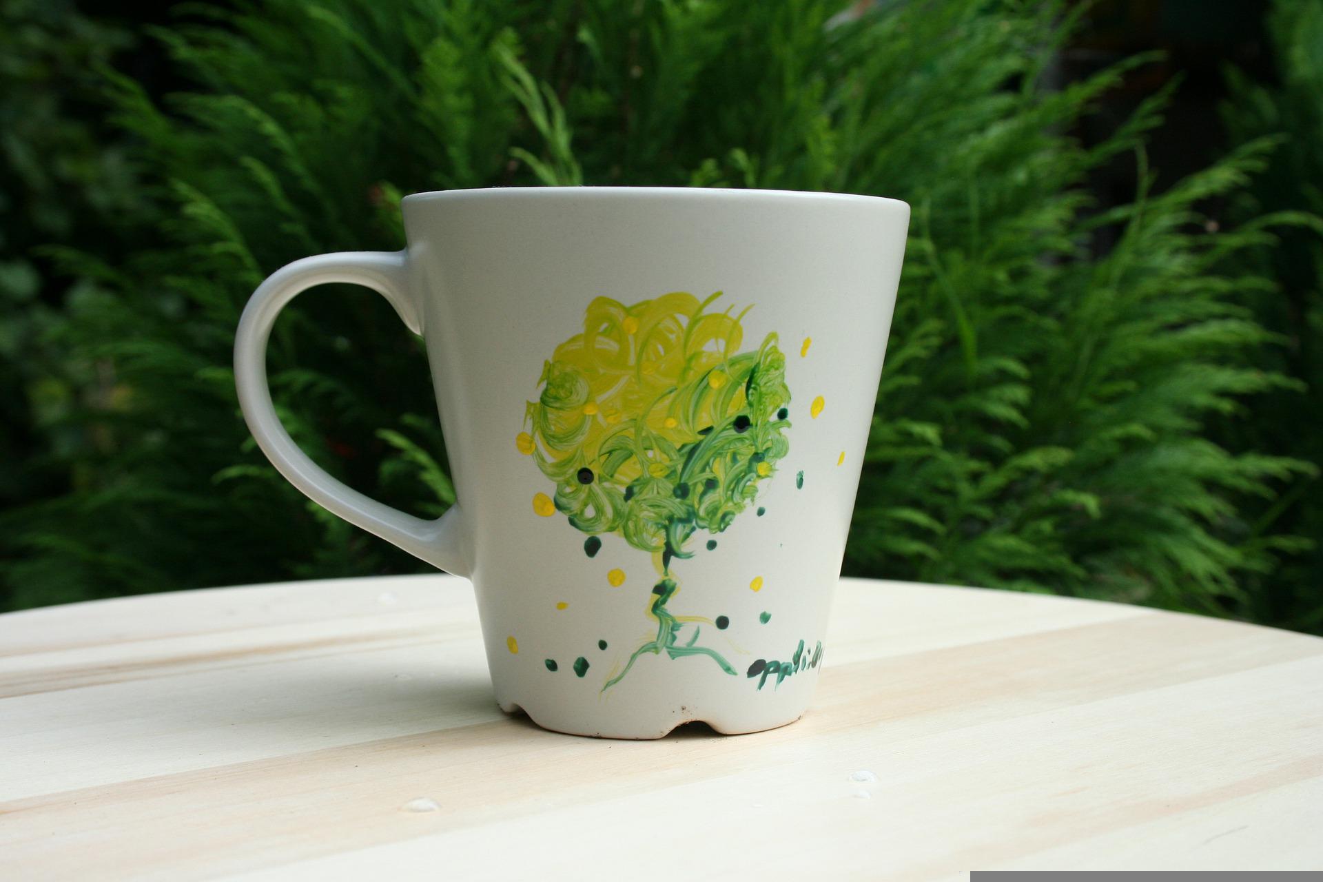 Caneca branca com o desenho de uma árvore feito a mão.