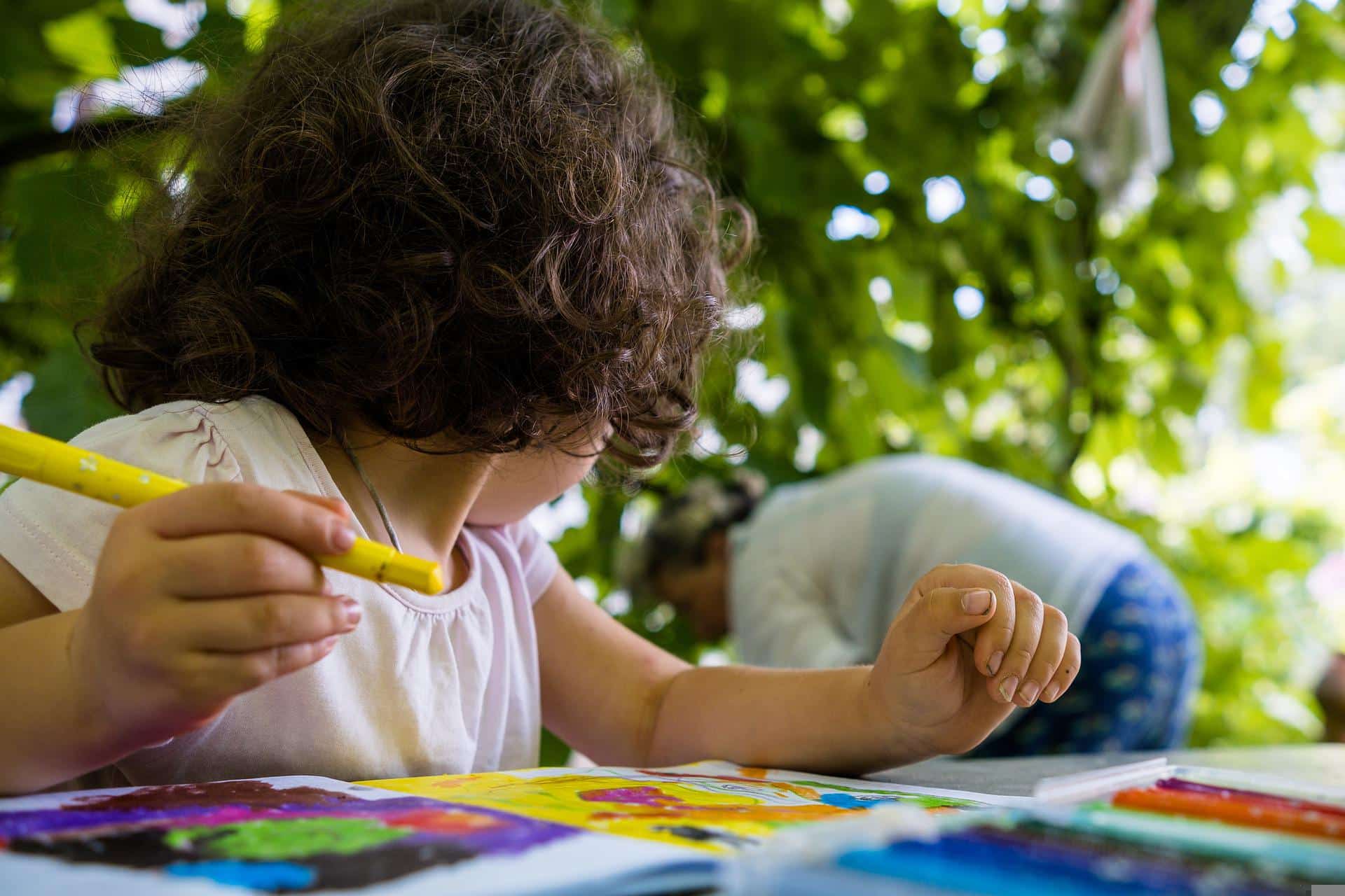 Criança colorindo com a avó ao fundo