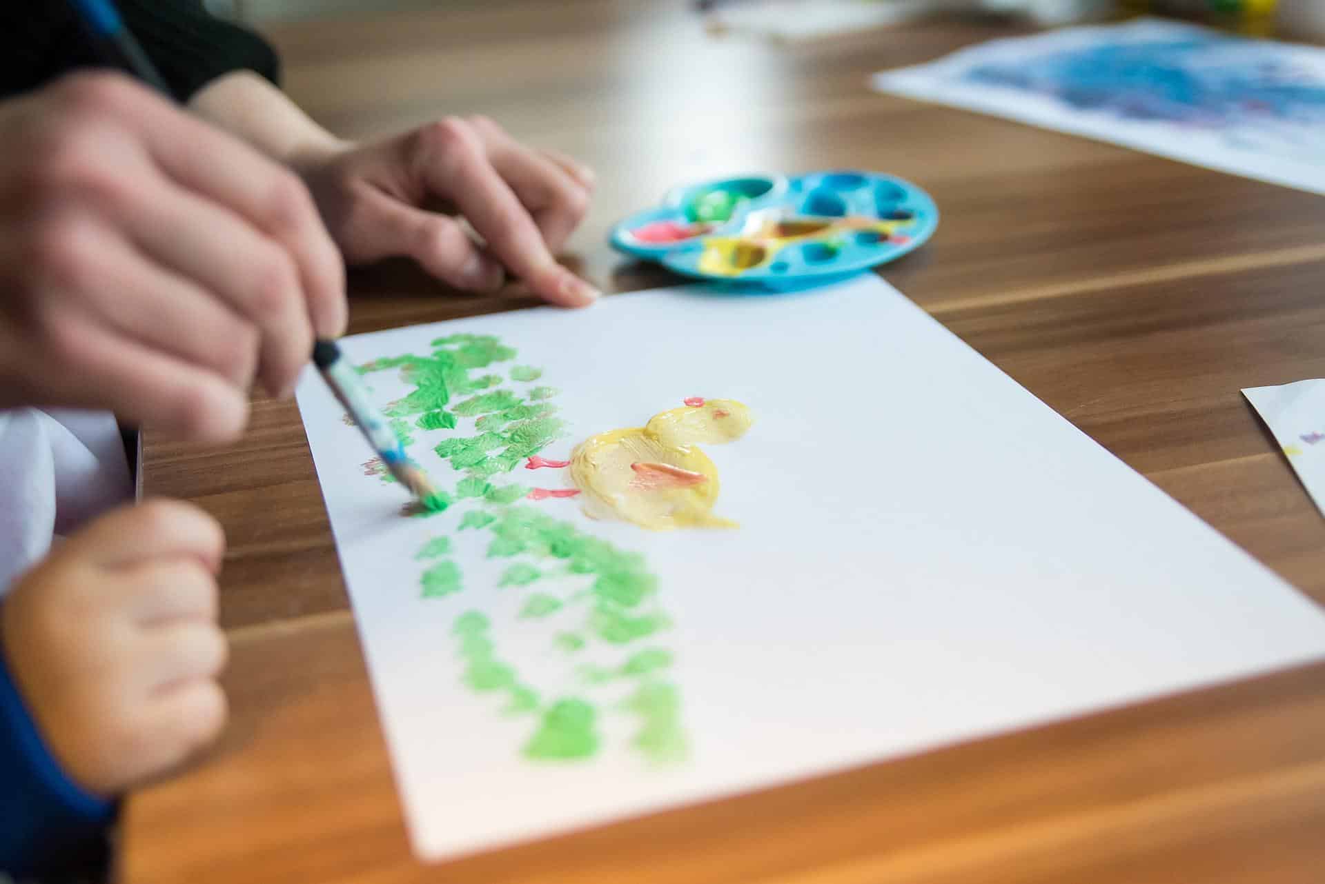 criança desenhando em uma filha de papel um pintinho com tinta