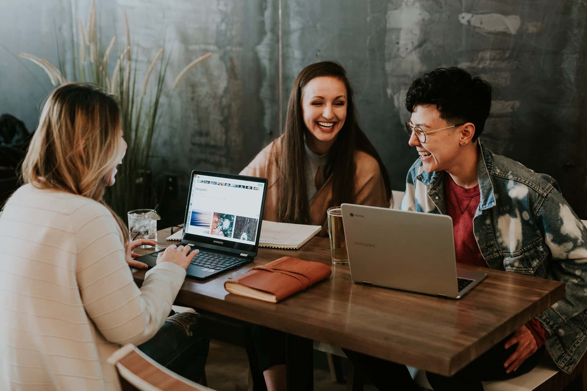Mulheres conversando e rindo em frente aos seus computadores