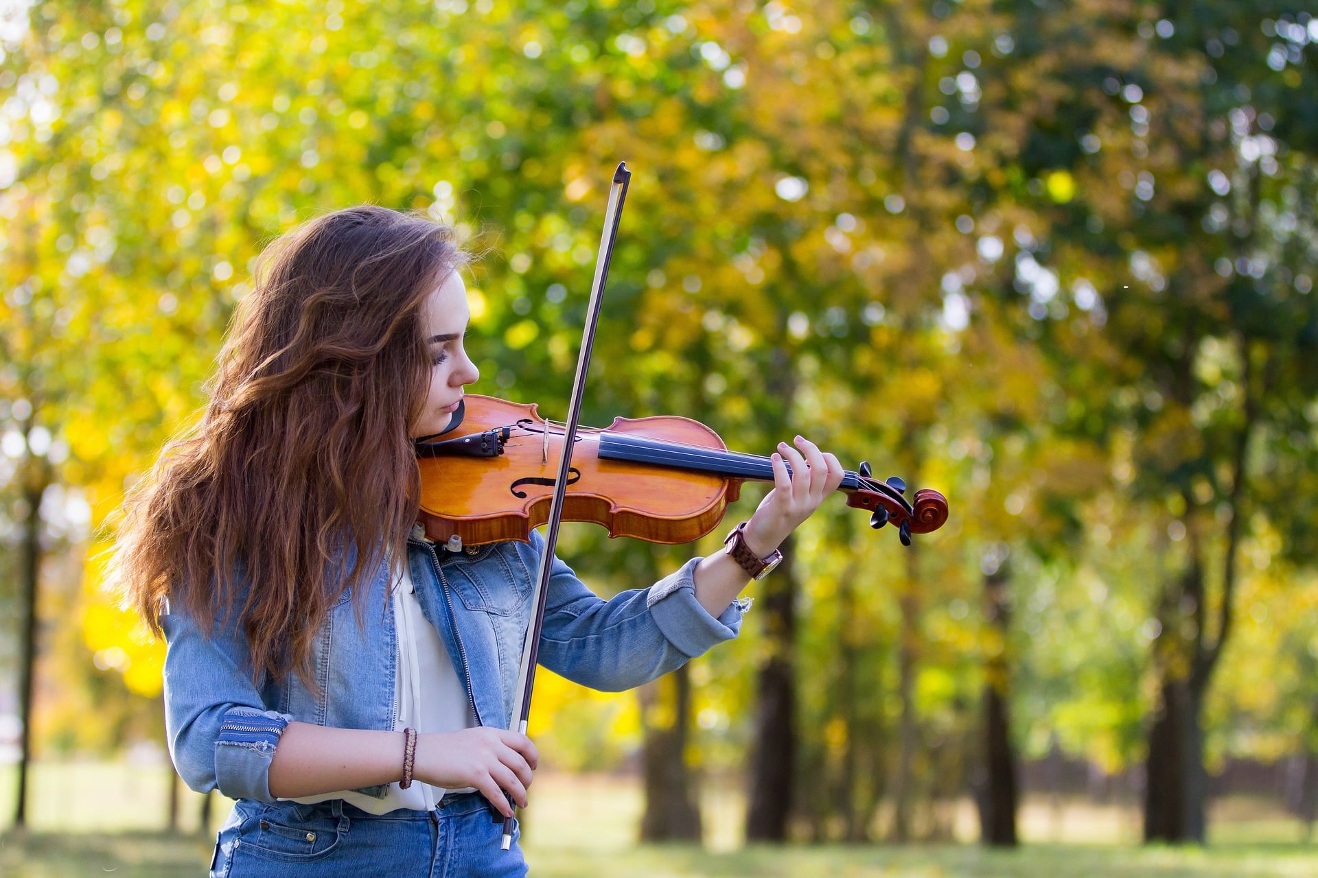 Mulher tocando violino em um parque.