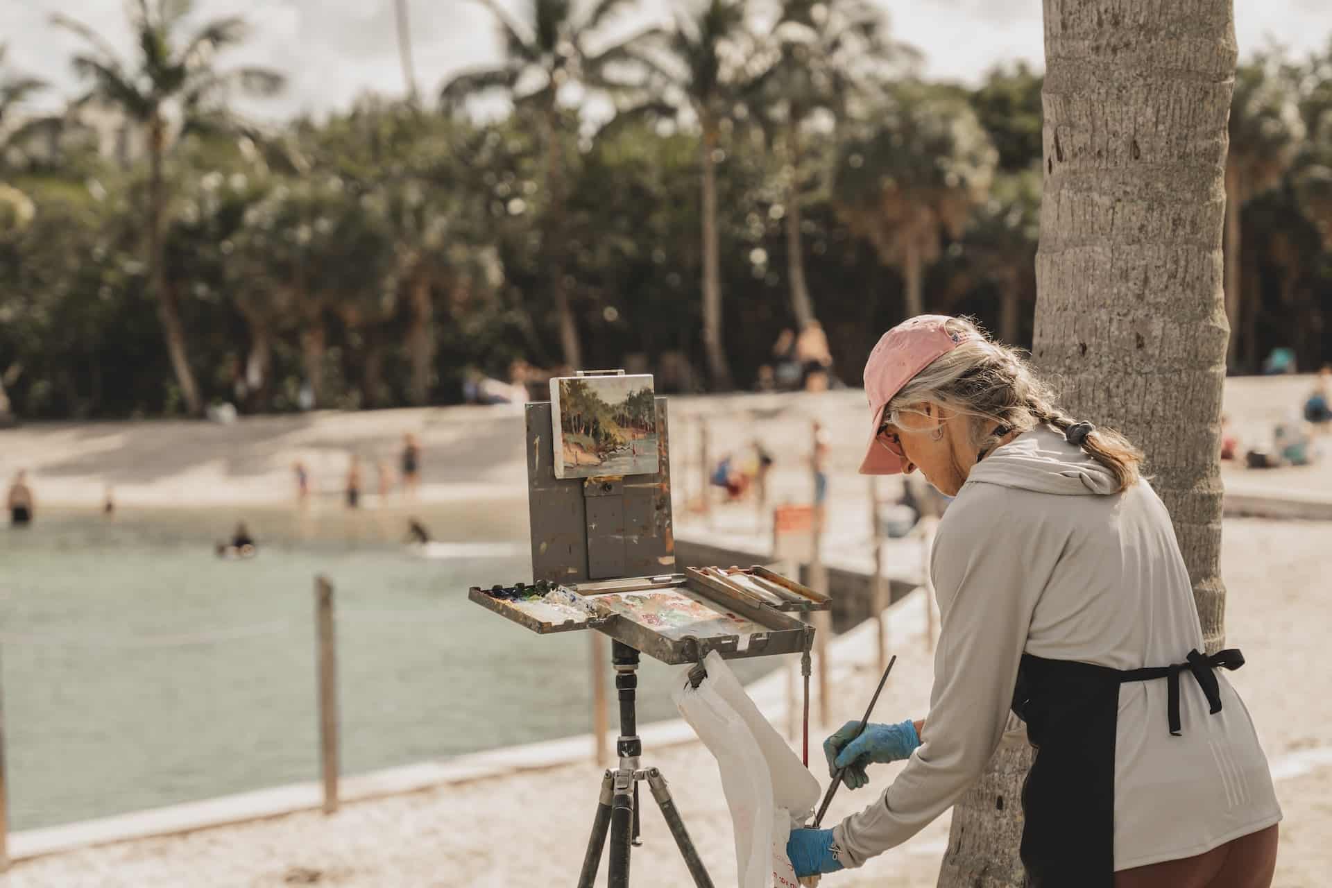 mulher pintando em um parque, de frente para um lago