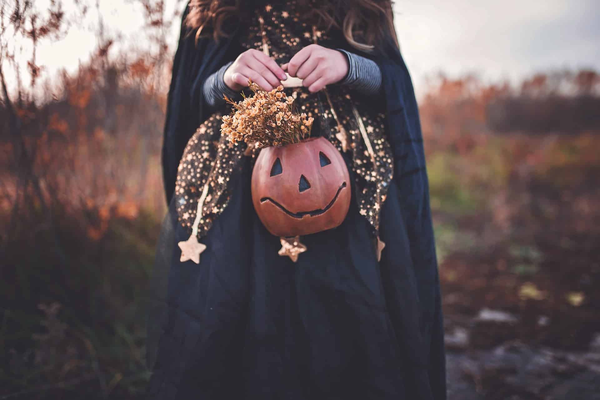 Pessoa com fantasia de halloween e bolsa de abóbora.