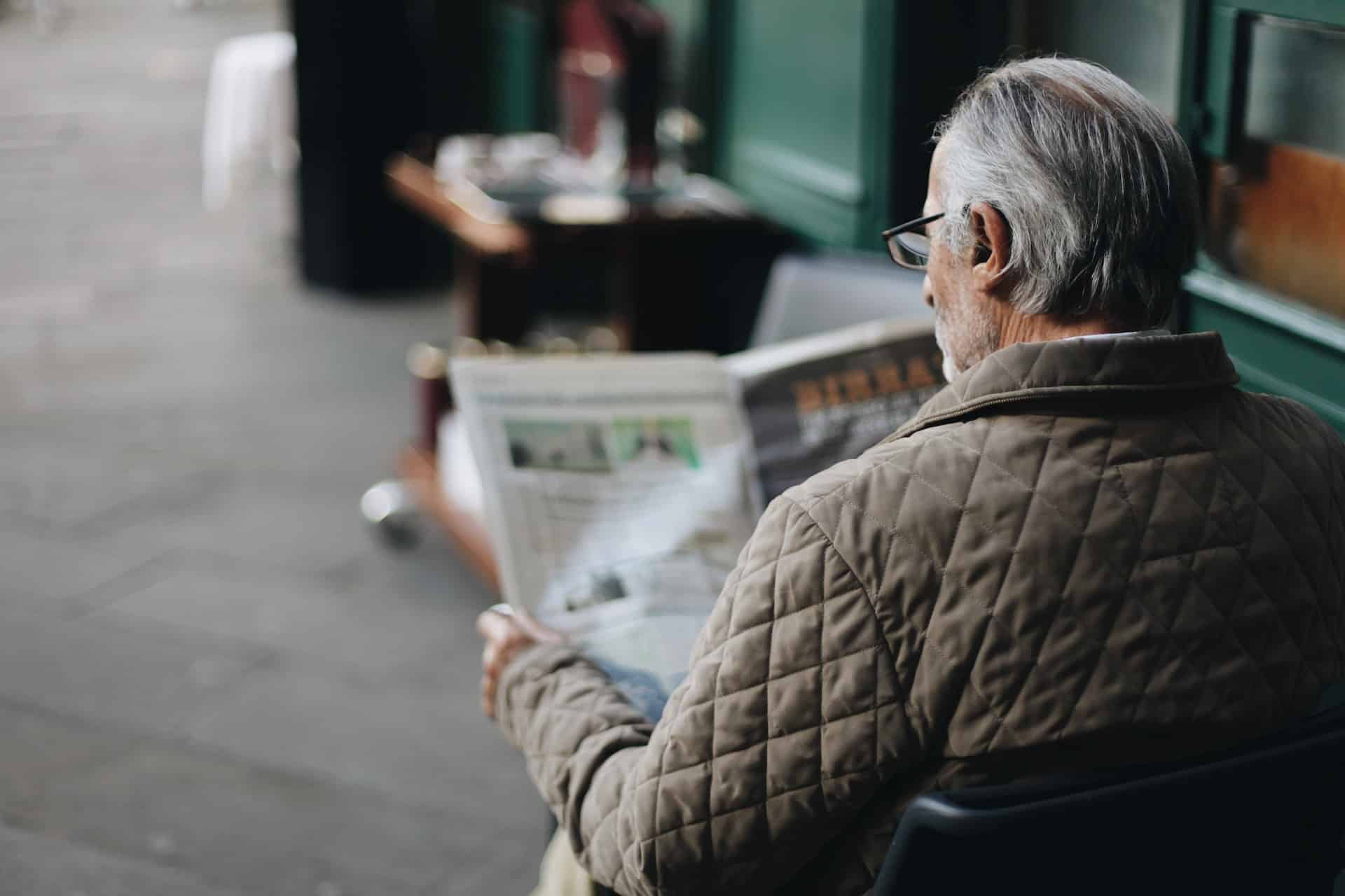 Senhor sentado lendo jornal
