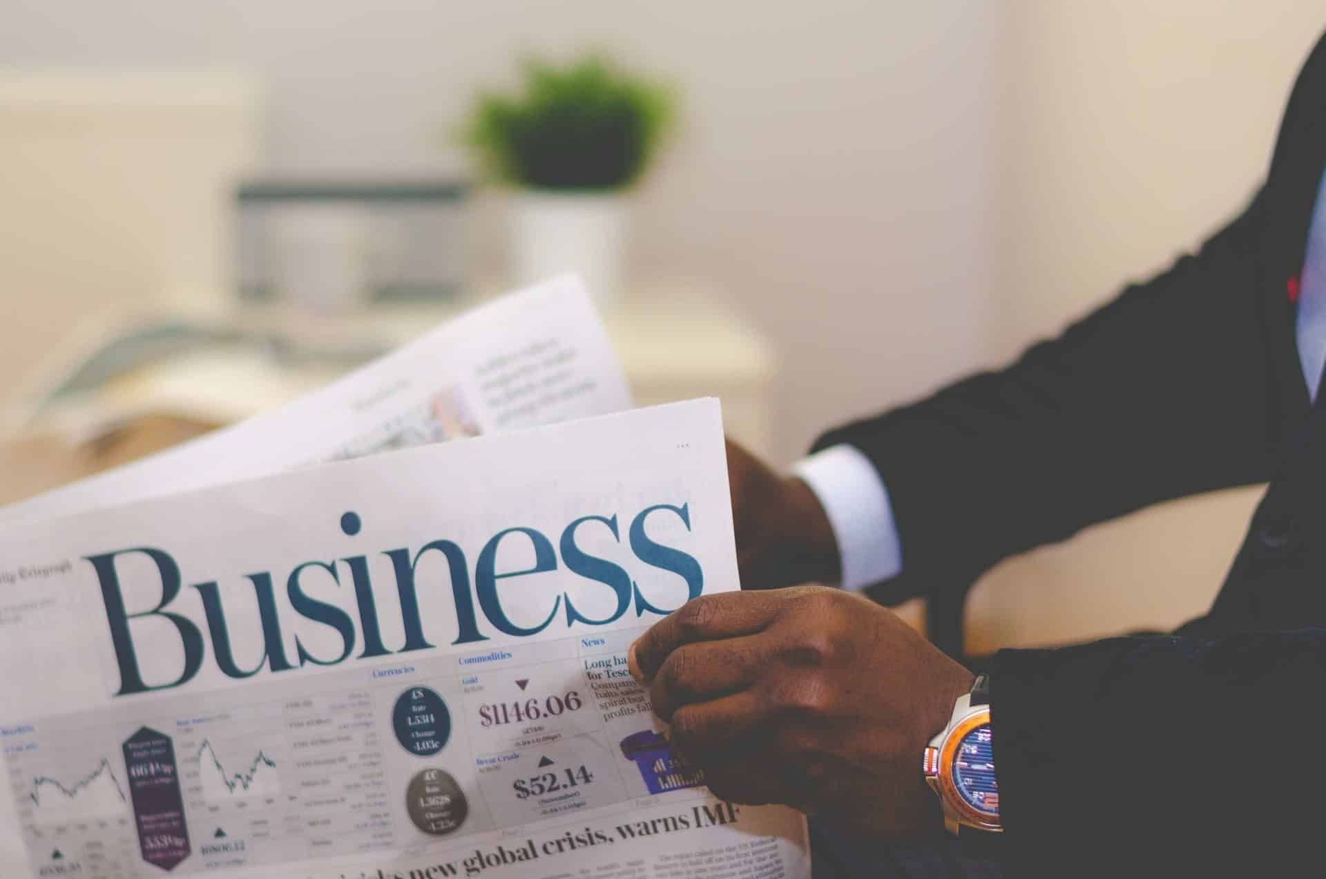 Mãos abrindo jornal de negócios