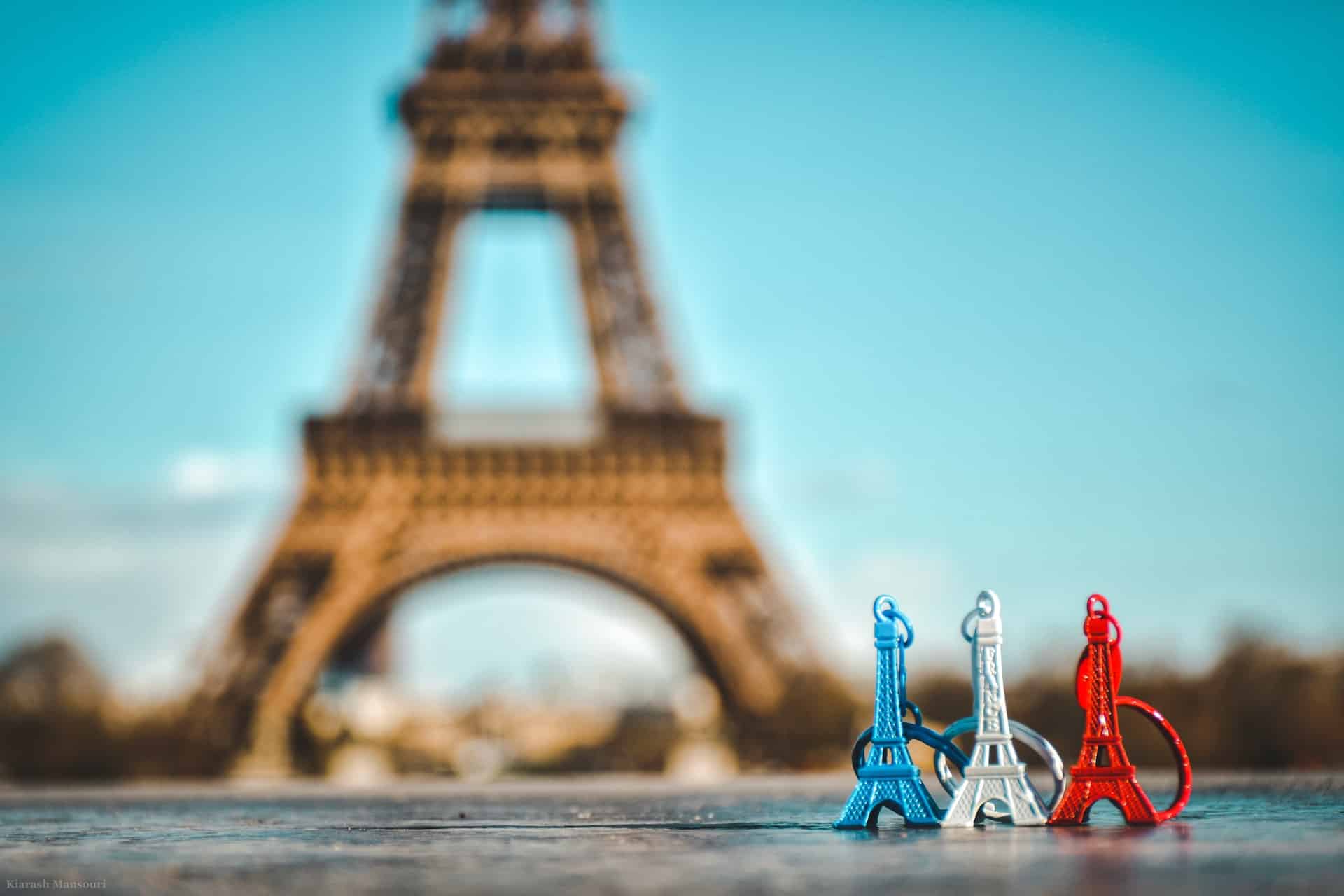 pequenos chaveiros de torres Eiffel enfileradas na frente da verdadeira torre