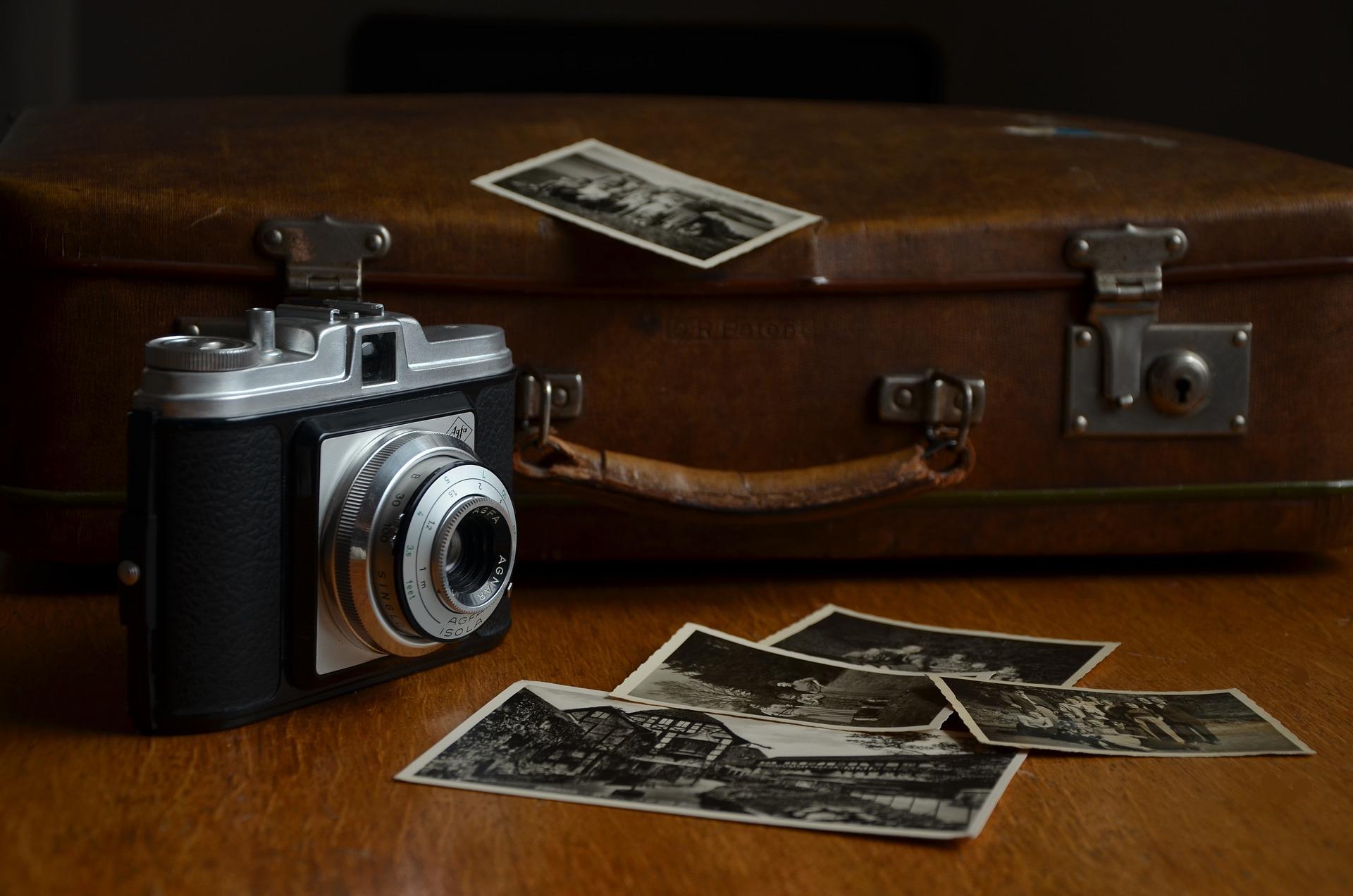 Mala antiga com uma câmera analógica e algumas fotografias em preto e branco.