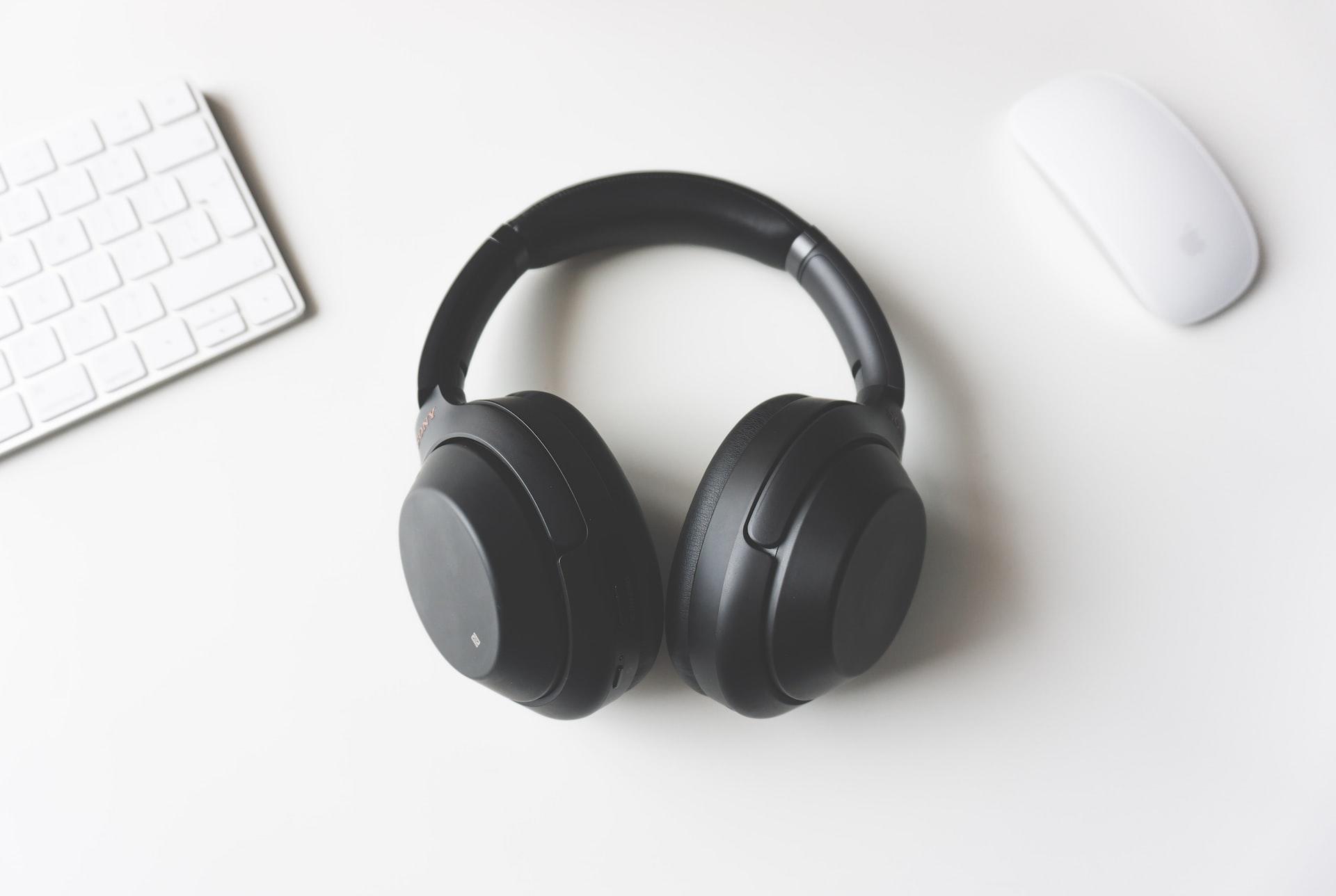 Headphones ao lado de um teclado e mouse em um fundo branco