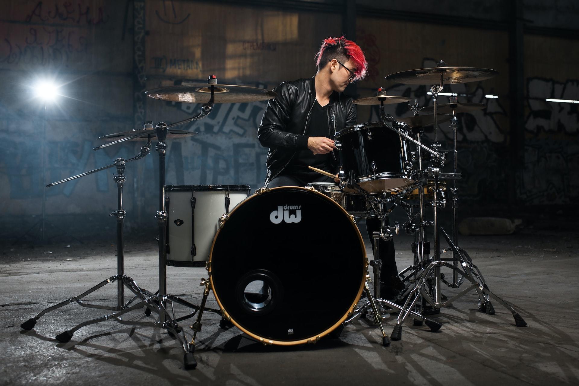 menino com mechas vermelhas tocando bateria