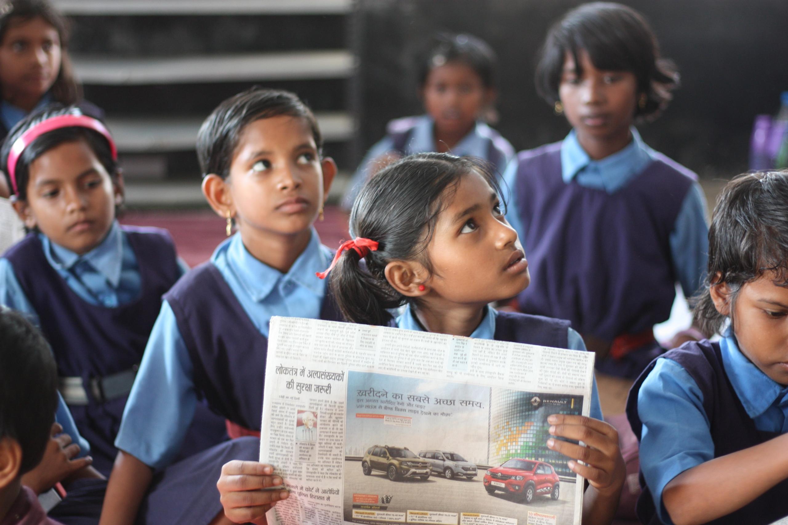Grupo de crianças na escola enquanto estão lendo o jornal