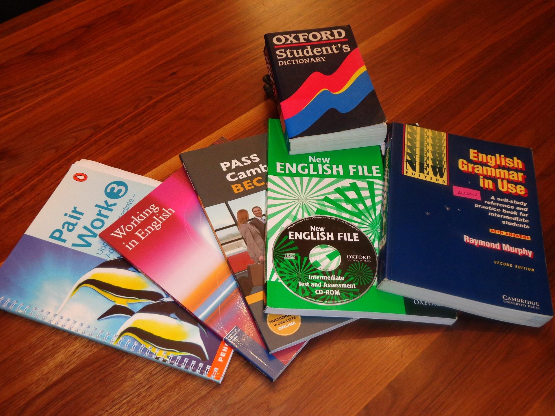 Coletânea de livros didáticos de inglês, sobrepostos em cima de uma mesa.