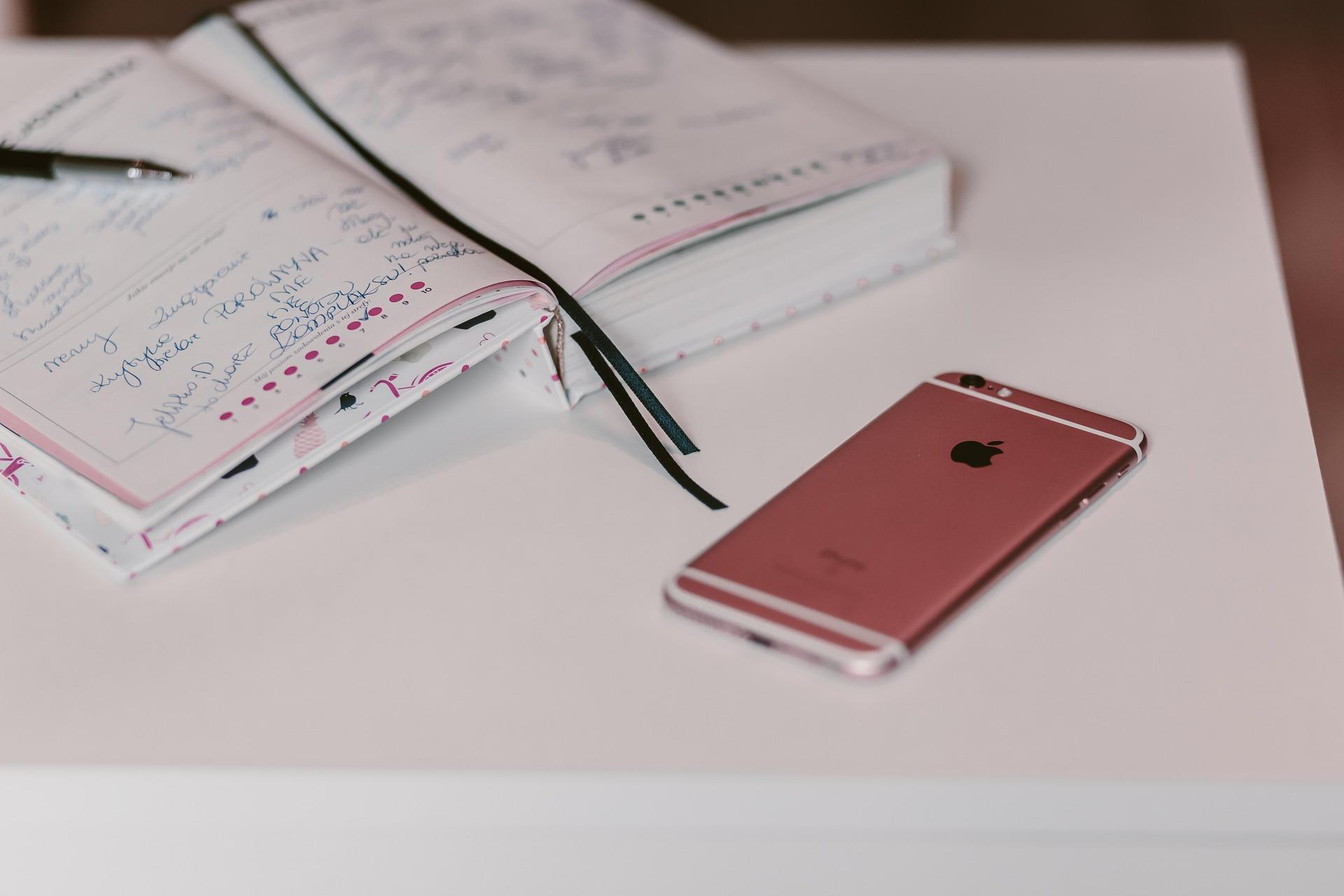 Um caderno aberto e um celular sobre a mesa