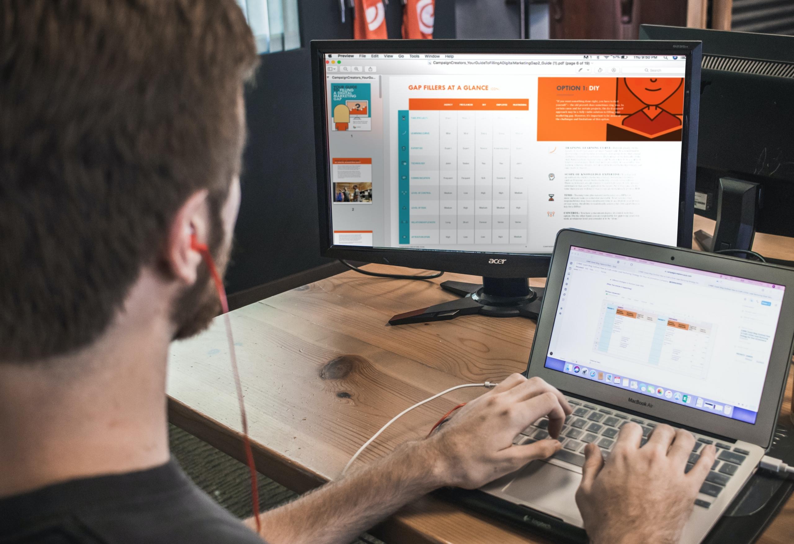 Profissional trabalhando home office com duas telas enquanto desenvolve planilhas em ambas