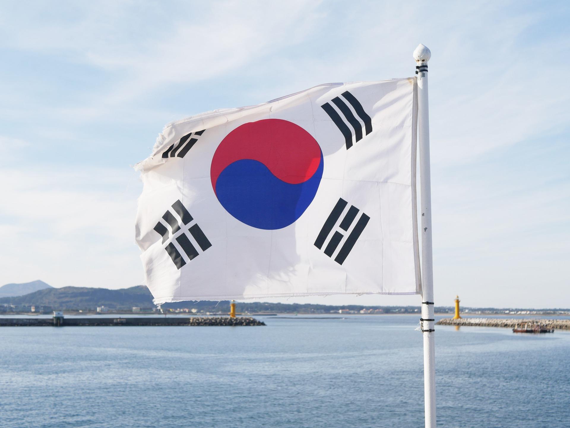 Bandeira coreana hasteada com céu e mar ao fundo. 