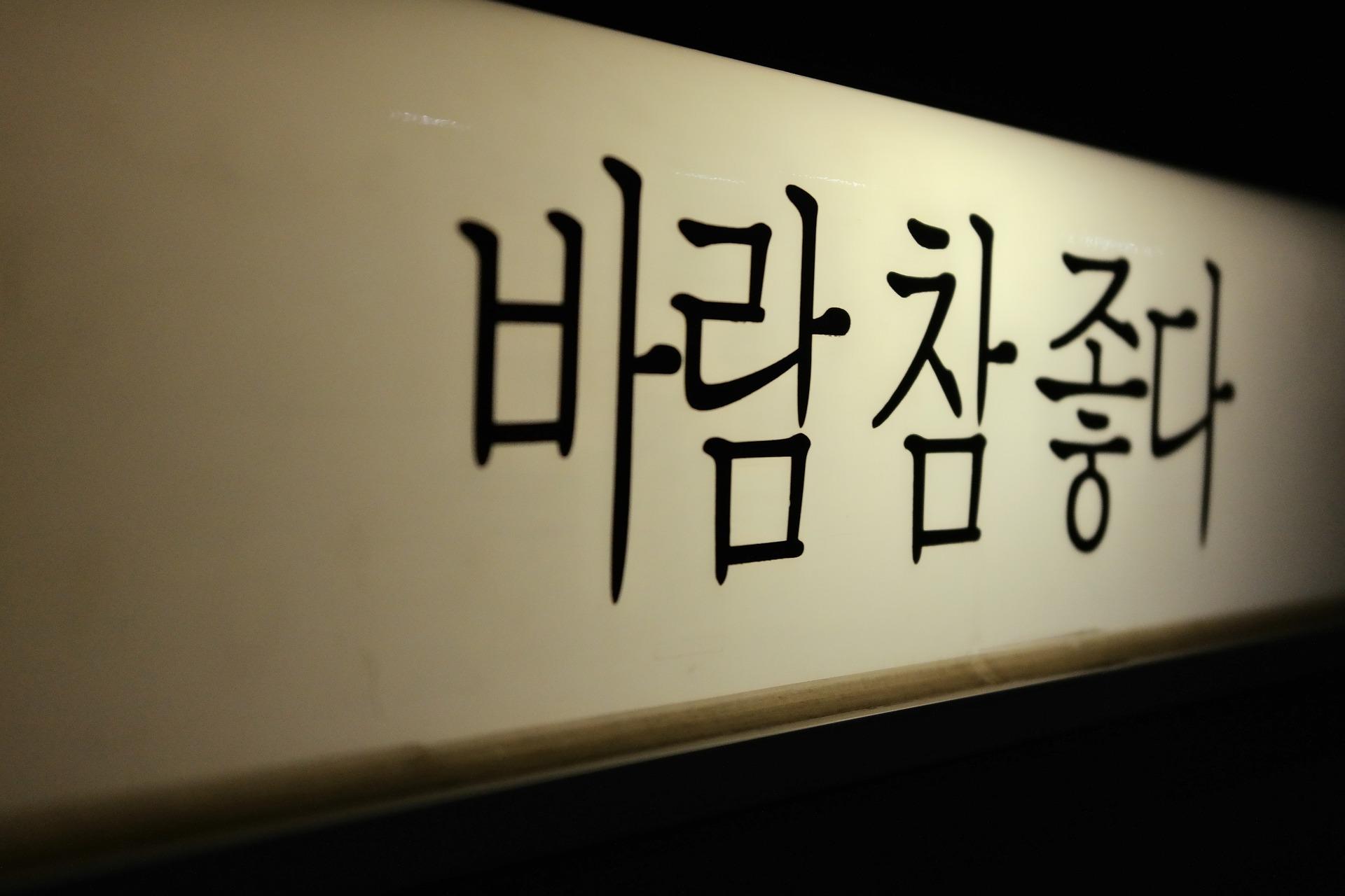 Letras coreanas pintadas em preto no branco. A imagem está em diagonal.