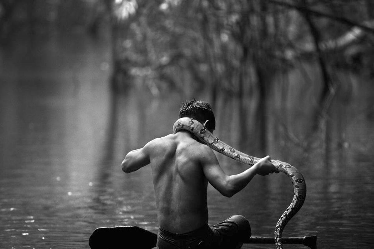 Homem com uma cobra no seu pescoço.