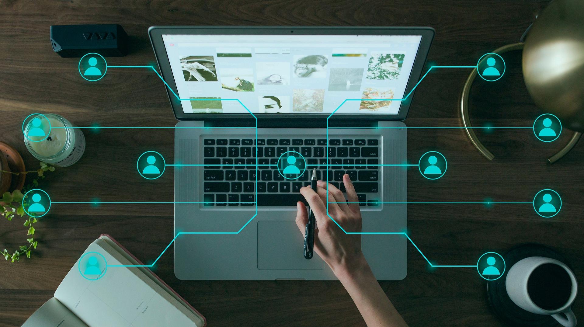 Foto de um computador com uma rede de pessoas conectadas em um desenho com ícones.