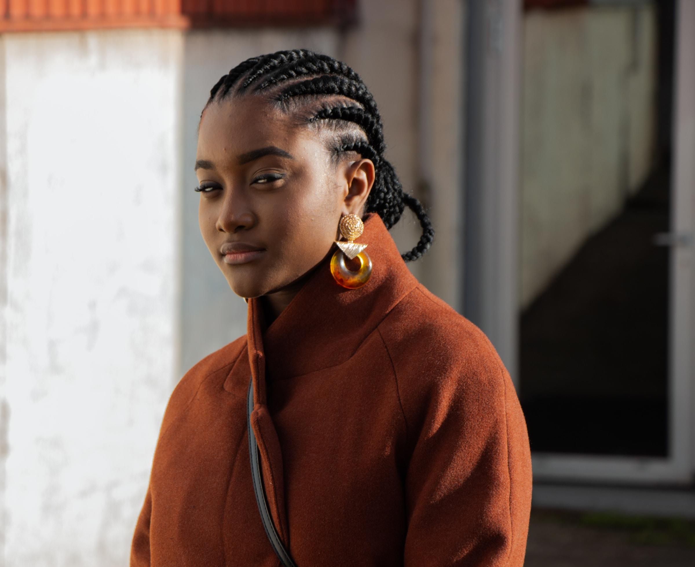 Mulher negra com tranças enquanto está em um espaço urbano