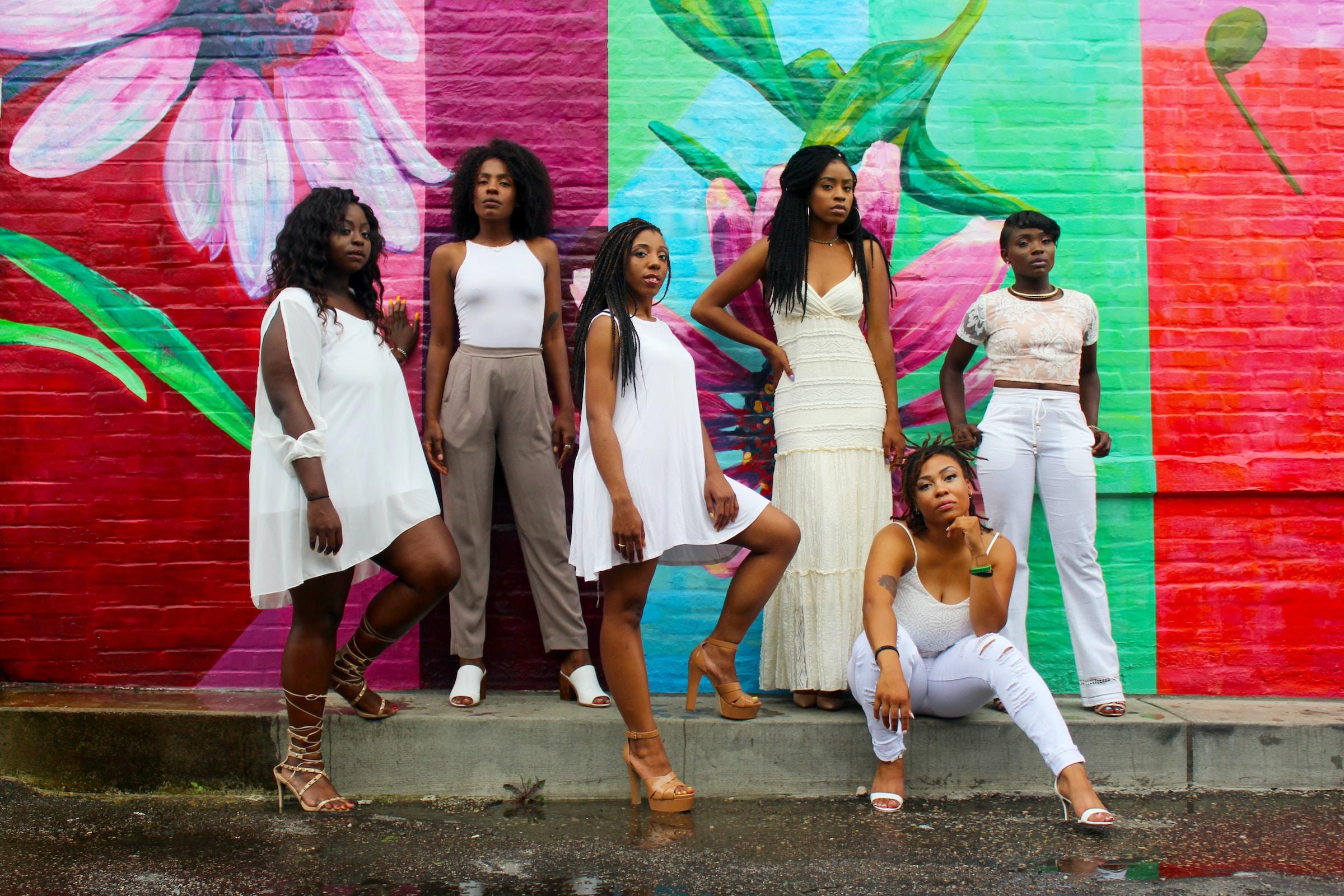 Mulheres reunidas usando roupas claras com fundo colorido