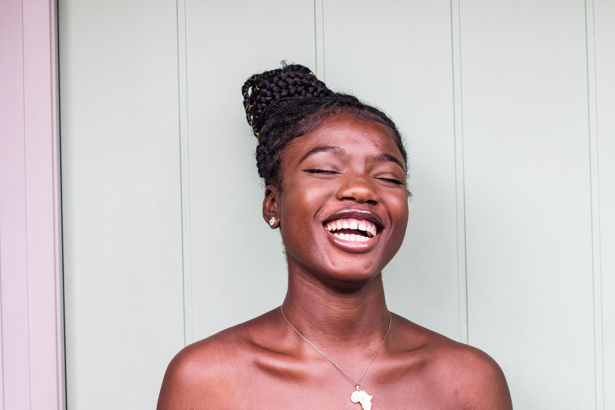Mulher negra sorrindo enquanto usa tranças afro no cabelo