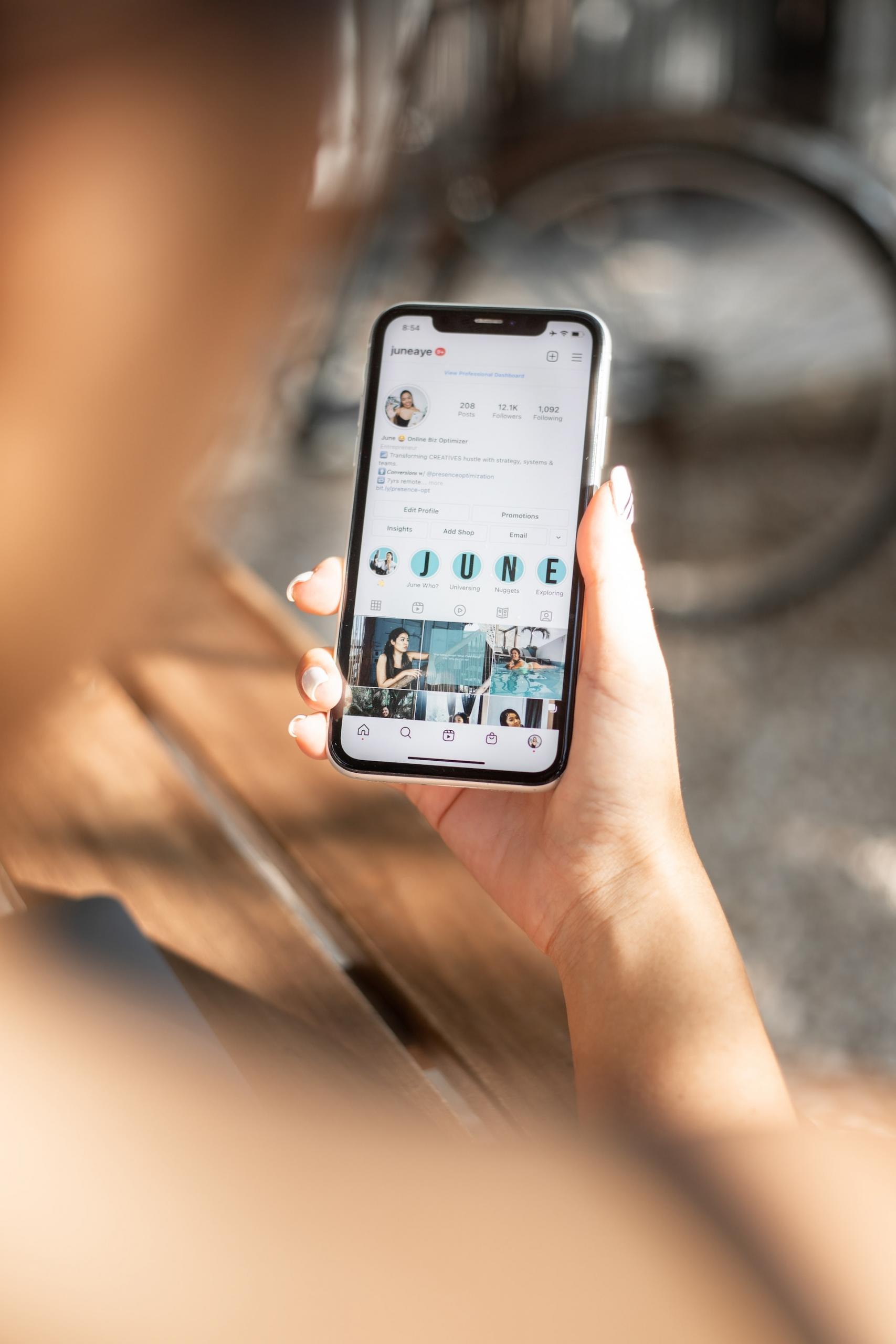 Mão segurando um smartphone com um perfil do Instagram aberto